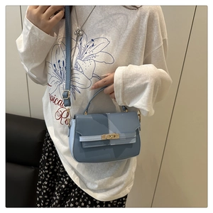 Detail shot of a blue color-block handbag with a metal lock worn by a model in lifestyle setting