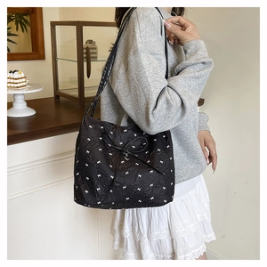 Detail der schwarzen Stepptasche mit Mini-Schleifen und Herzanhänger für Damen