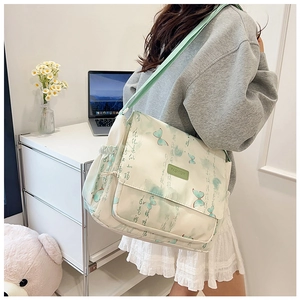 Lifestyle shot of large crossbody bag with butterfly prints and green wide shoulder strap