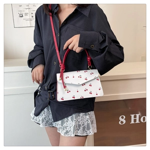 Détail d'un mini sac en cuir blanc avec imprimé cerise et bandoulière réglable