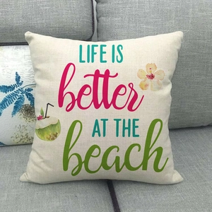 Federa per cuscino quadrata color crema con stampa spiaggia tropicale su un divano grigio
