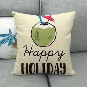 Close-up of linen cushion with tropical coconut print and Happy Holiday text on grey sofa