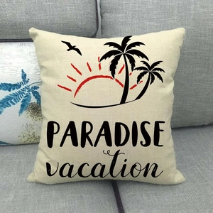Detail of linen pillowcase with Paradise vacation text and tropical print on grey sofa