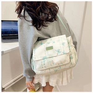 Détail du sac messager en toile crème avec imprimé papillon vert et calligraphie