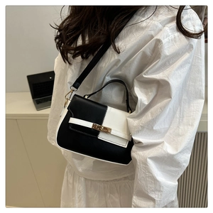 Close-up of a black and white patchwork Kelly bag with golden twist-lock and shoulder strap
