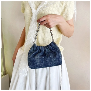 Detail of blue denim bucket bag with silver beads handle and sparkling finish texture