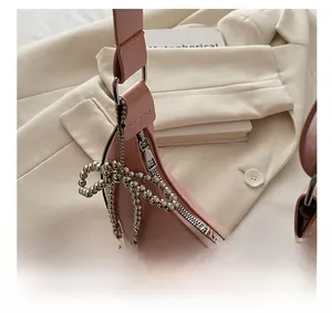 Détail du sac lune en cuir verni rose avec fermeture éclair argentée et nœud en perles