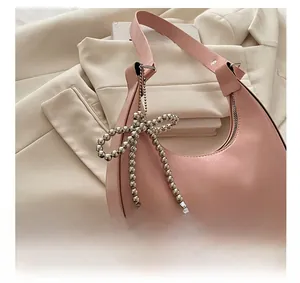 Vue détaillée du sac croissant rose avec breloque nœud en perles de métal argenté