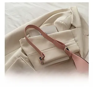 Sac hobo demi-lune rose avec breloques en perles argentées sur un blazer beige