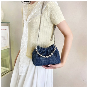 Detail of blue denim cloud bucket bag with silver bead handle and metal chain strap