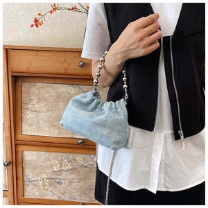 Close-up of light blue denim cloud bucket bag with silver bead handle and chain strap