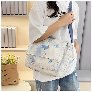 Detail showing the adjustable blue wide strap and rubber fashion logo on messenger bag