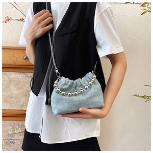 Detail of light blue denim bucket bag with silver chain and decorative beads on the side