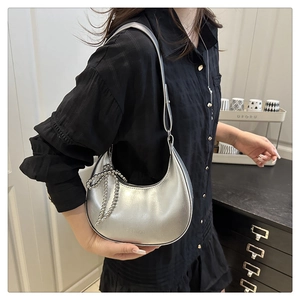Détail du sac hobo argenté avec pendentif nœud perlé et logo fashion en relief