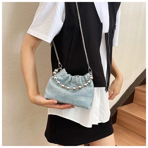 Detail of light blue cloud bag with chunky silver bead handle and chain strap on stairs