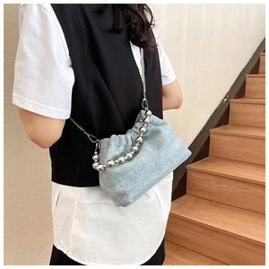Detail view of denim bucket bag with silver bead chain strap on model shoulder
