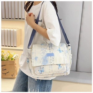 Détail du sac bandoulière en toile avec imprimés papillons bleus et calligraphie à l'encre