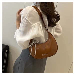 Détail d'un sac demi-lune marron avec breloque nœud argenté et bandoulière réglable