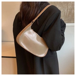 Khaki retro glossy faux leather underarm bag worn on shoulder with dark blazer
