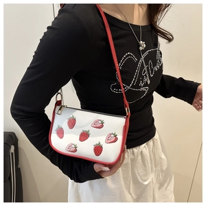 Detail view of the red strawberry print on white PU leather bag with metal zipper