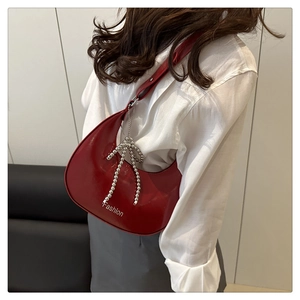 Détail du sac lune en cuir verni rouge avec imprimé mode et breloque nœud argenté