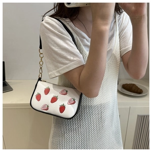 Close-up of strawberry print shoulder bag with black strap and gold chain detail