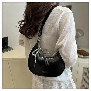 Close-up of black crescent hobo bag with silver beaded bow charm and fashion logo
