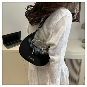 Detail of a black hobo bag with silver bow charm and Fashion print on a sleek finish