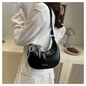 Detailed view of black patent leather hobo bag with silver chain bow accessory