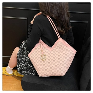 Pink and beige monogram tote bag with V-shaped opening and gold M pendant on a model