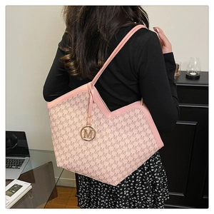 Détail du sac cabas rose avec motif monogramme, pendentif doré et ligne en V