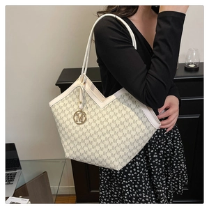 Détail du sac cabas beige avec motifs M imprimés et pendentif doré en métal en forme de M