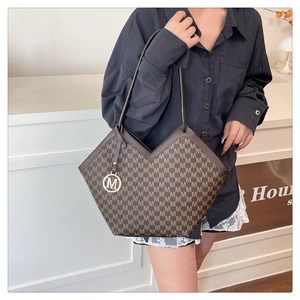Close-up of deep brown tote bag with V-shaped top, M-letter patterns and metal pendant