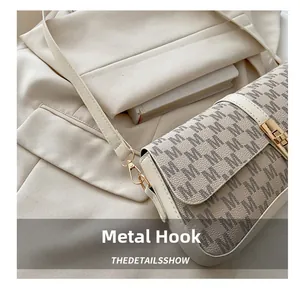 Vue détaillée du sac à main crème avec crochets dorés et motif monogramme M chic