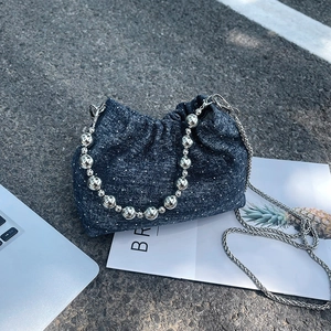 Denim chain bucket bag with silver beads handle and white polka dots on grey surface