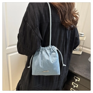 Detail of light blue denim bucket bag with drawstring strap and metallic logo