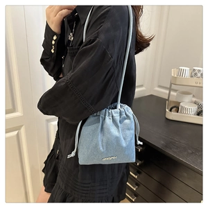 Dettaglio della borsa a secchiello in denim azzurro con logo e chiusura a coulisse