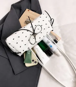 Détail du sac sous l'aisselle en dentelle blanche avec nœud noir et pendentif cœur et espace