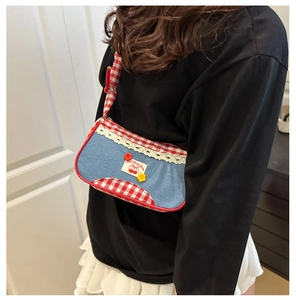 Close-up of a plaid shoulder bag featuring denim patchwork and sweet cherry bear label