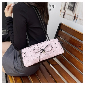 Détail du sac à bandoulière plissé rose clair avec nœuds noirs et pendentif cœur