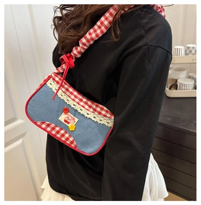 Detail of blue denim bag with red checkered trim and sweet cherry embroidered patch