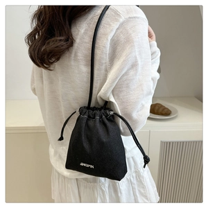Detail of a casual black denim drawstring bucket bag with JINGPIN embroidery on the side