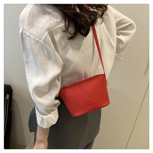 Detail of red pebbled leather bucket bag with brand logo worn with a white shirt