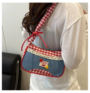 Detail of blue denim shoulder bag with red plaid handles and sweet cherry patch