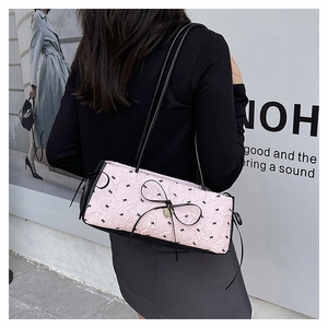 Détail du sac bandoulière rose à motif nœuds avec rubans noirs et texture plissée