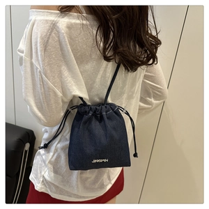 Détail du sac seau en denim bleu foncé avec cordon de serrage et logo en métal