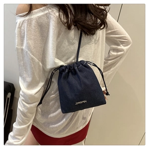 Detail shot of mini denim bucket bag with drawstring closure and metal logo plaque