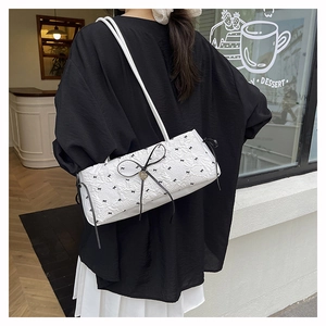 Détail du sac sous le bras texturé blanc avec grand nœud noir et rubans élégants