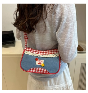 Detail of sweet cherry denim shoulder bag with red plaid trim and lace decoration