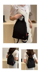 Detail view of black nylon backpack showing red FASHION label and metal logo